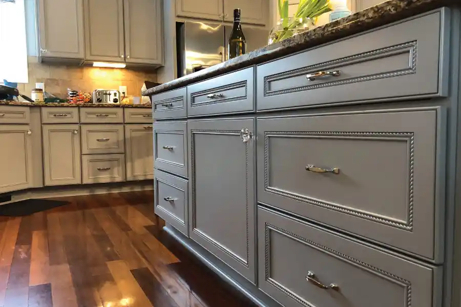 Bright kitchen with newly refinished white cabinets, updated hardware, and a contrasting dark countertop.